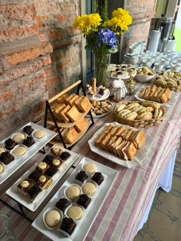 Montaje completo con pastelería, sándwiches y flores amarillas