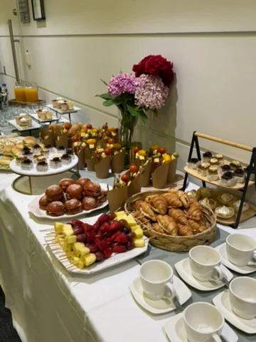 Mesa de coffee break con brochetas de fruta, dulces y tazas de café